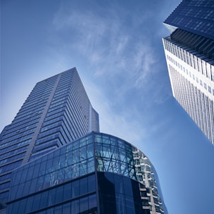 two tall buildings with glass windows against a blue sky
