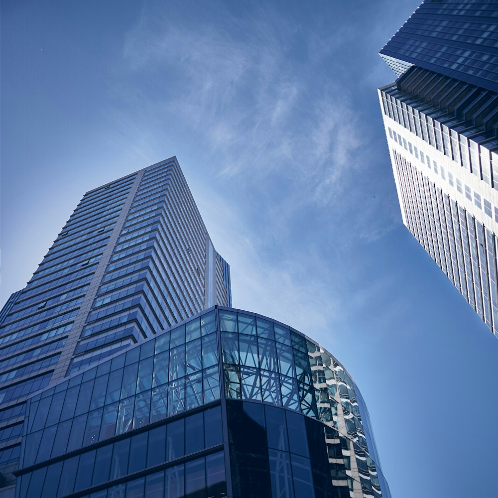 two tall buildings with glass windows against a blue sky