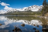 Emerald Lake reflecting lush green forests and snow-capped mountains on a calm day.