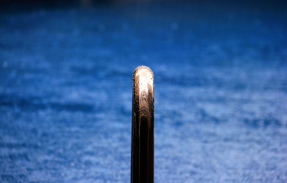 a close up of a metal pole with water in the background