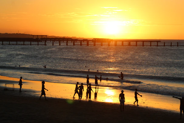 A group of friends playing frisbee on the beach at sunset, laughter and joy in the air.