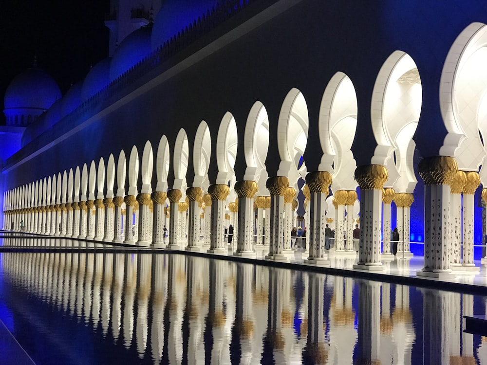 a row of white and gold arches next to a body of water