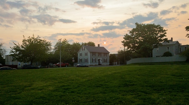 Image of a happy homeowner standing in front of their house with a calm neighborhood in the background.