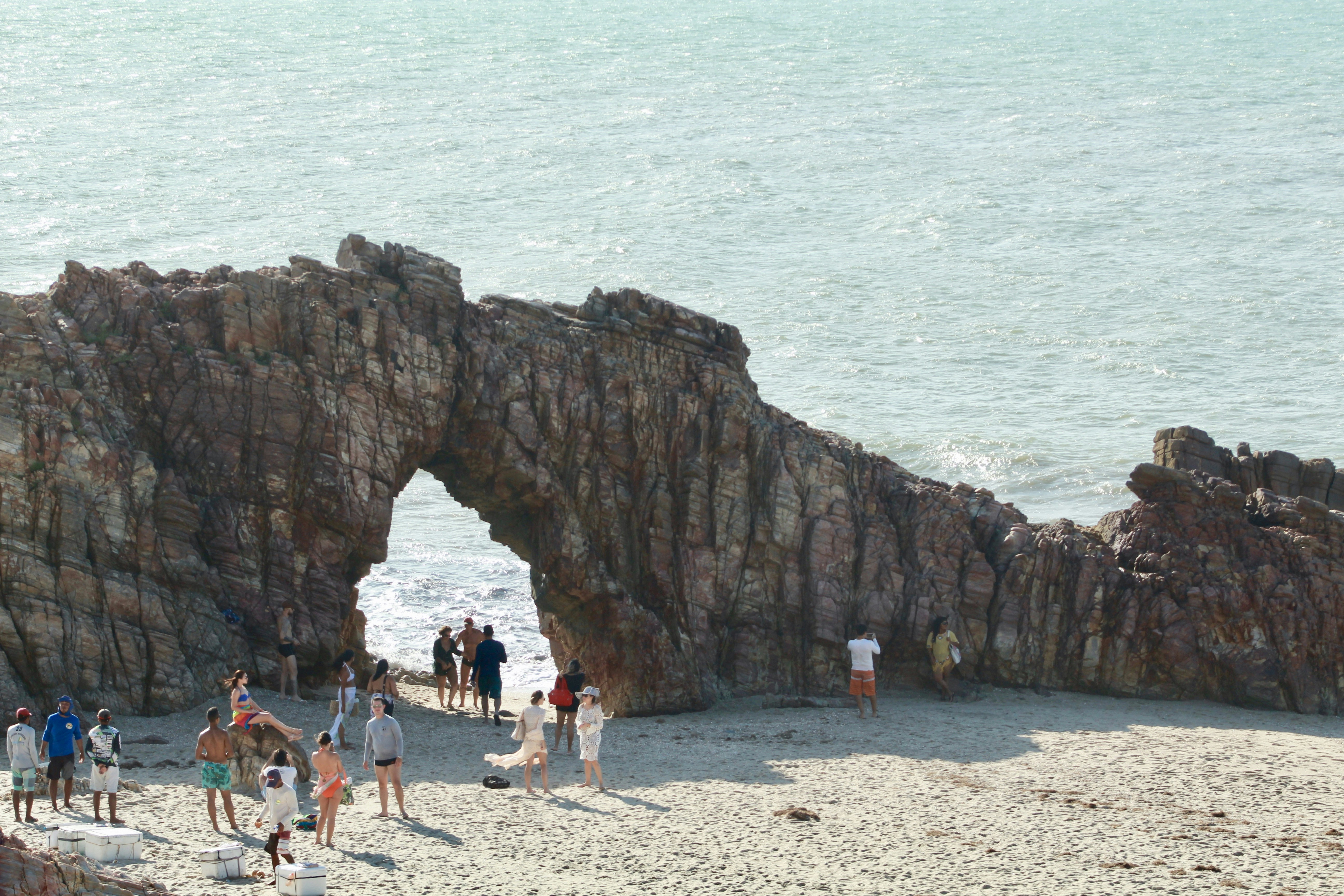 group of people standing beside brown rock formation