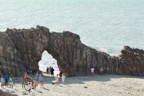 group of people standing beside brown rock formation