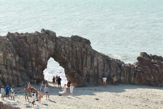 group of people standing beside brown rock formation