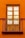A wooden window with six glass panes is set into a bright, orange wall. Iron railings form a small balcony in front of the window, adding a decorative element.