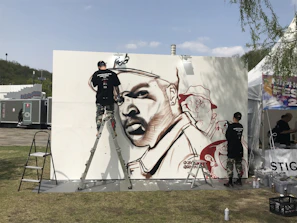 Artist painting a large-scale urban art piece in a studio setting.