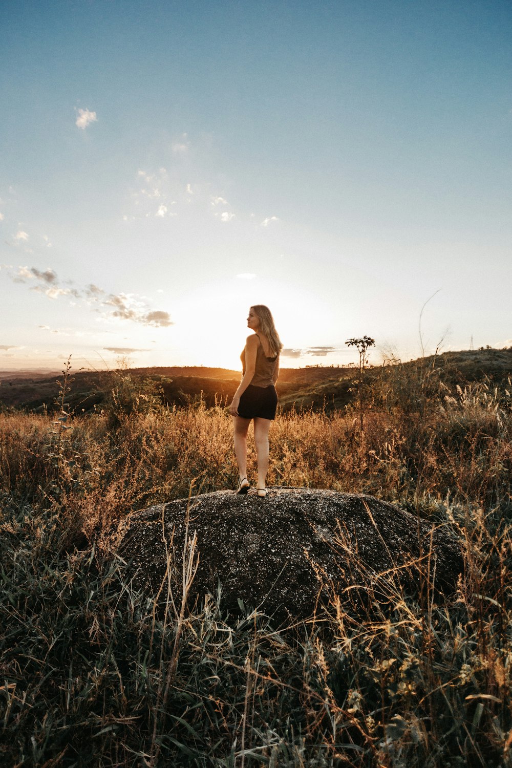 woman standing on top of rock during golden hour