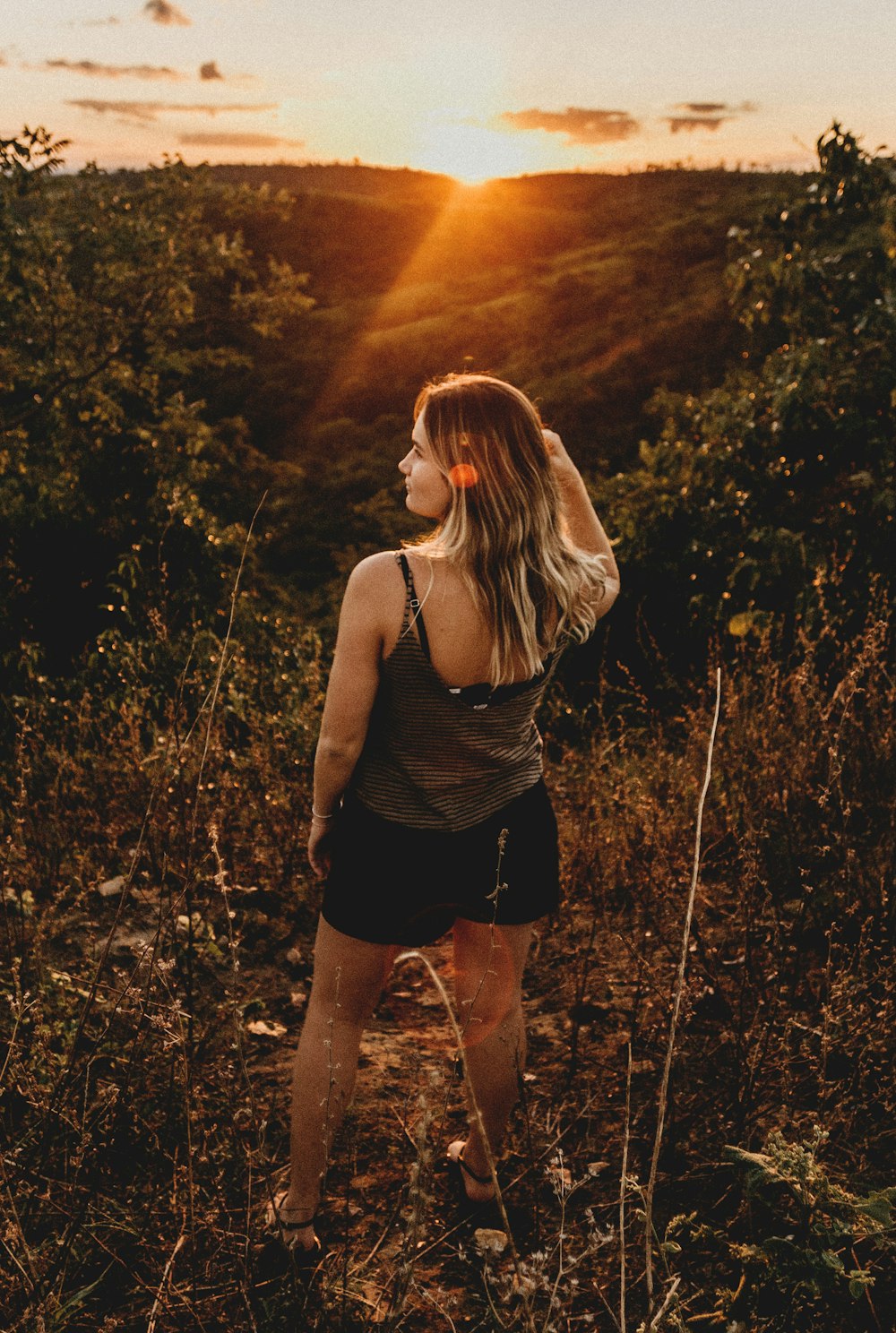 woman standing in green grass during golden hour