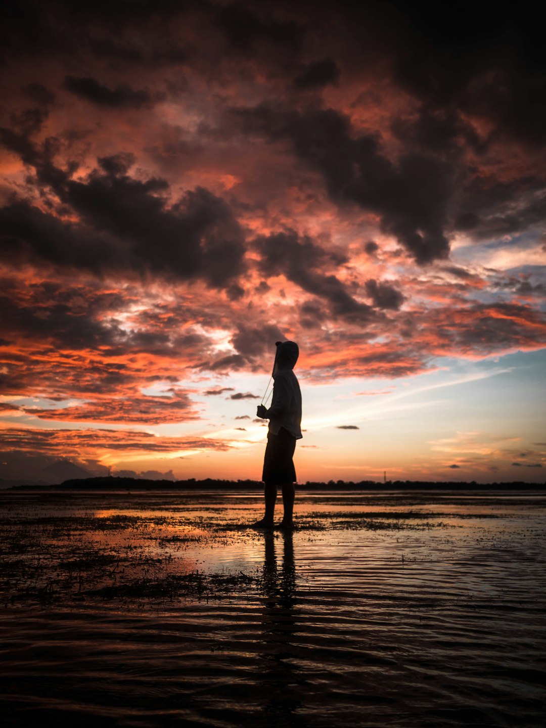 man standing in seashore during sunset