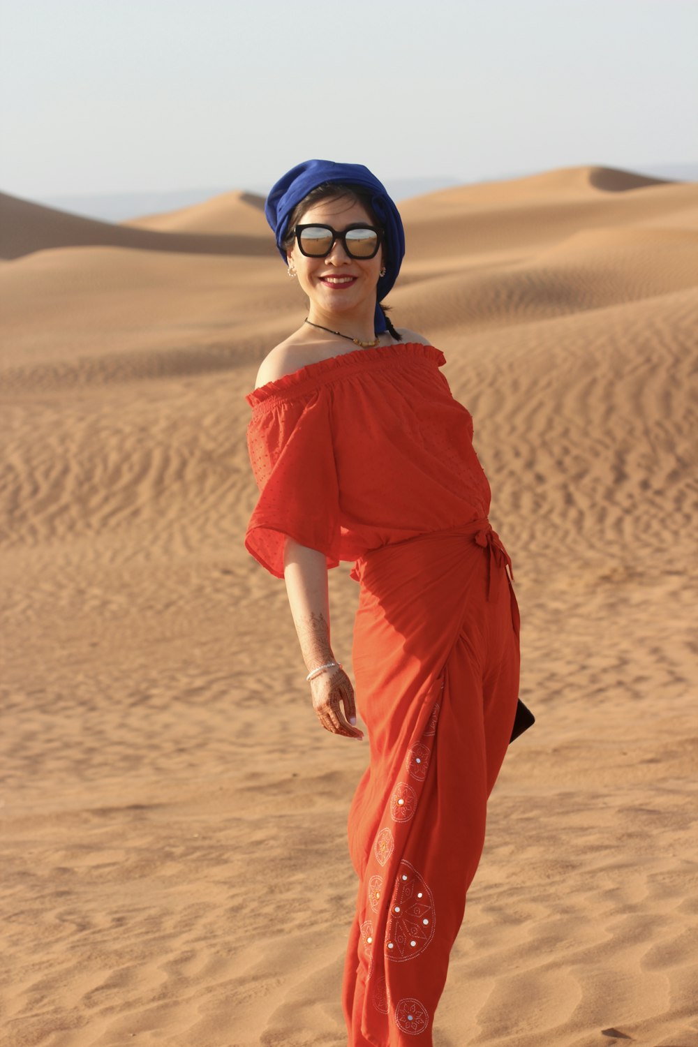 standing woman in red dress at sand dunes during daytime