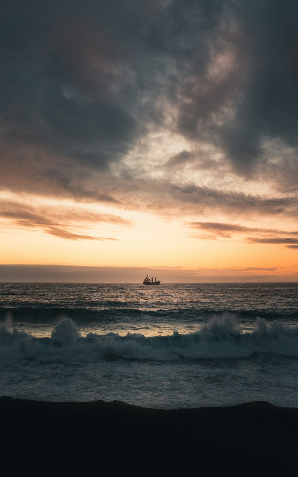 view of boat on the sea under dark clouds