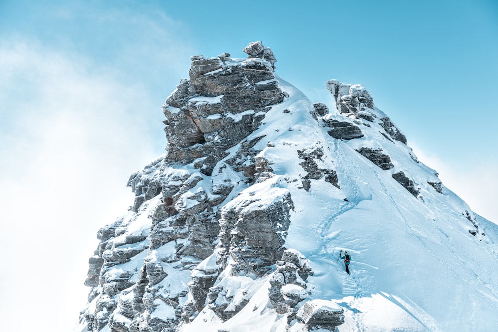person near top of a snow capped mountain during daytime