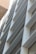 A modern building facade with a series of horizontal slats or louvers, creating a pattern of lines and shadows. The facade is composed of metallic and glass materials, reflecting light and capturing an urban architectural design.