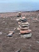 Close-up of smooth river stones stacked in a balanced pile on a sandy shore.