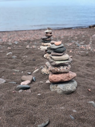 Close-up of smooth river stones stacked in a balanced pile on a sandy shore.