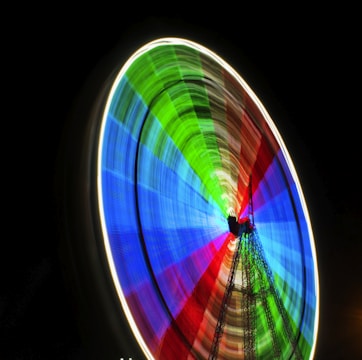 a colorful ferris wheel spinning in the dark