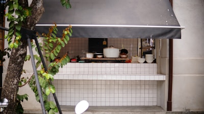A sleek stainless steel portable outdoor kitchen set up on a sunny patio with grilling tools neatly stored.