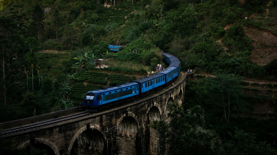 Aerial view of a blue Sri Lanka train winding between green hills and tea estates