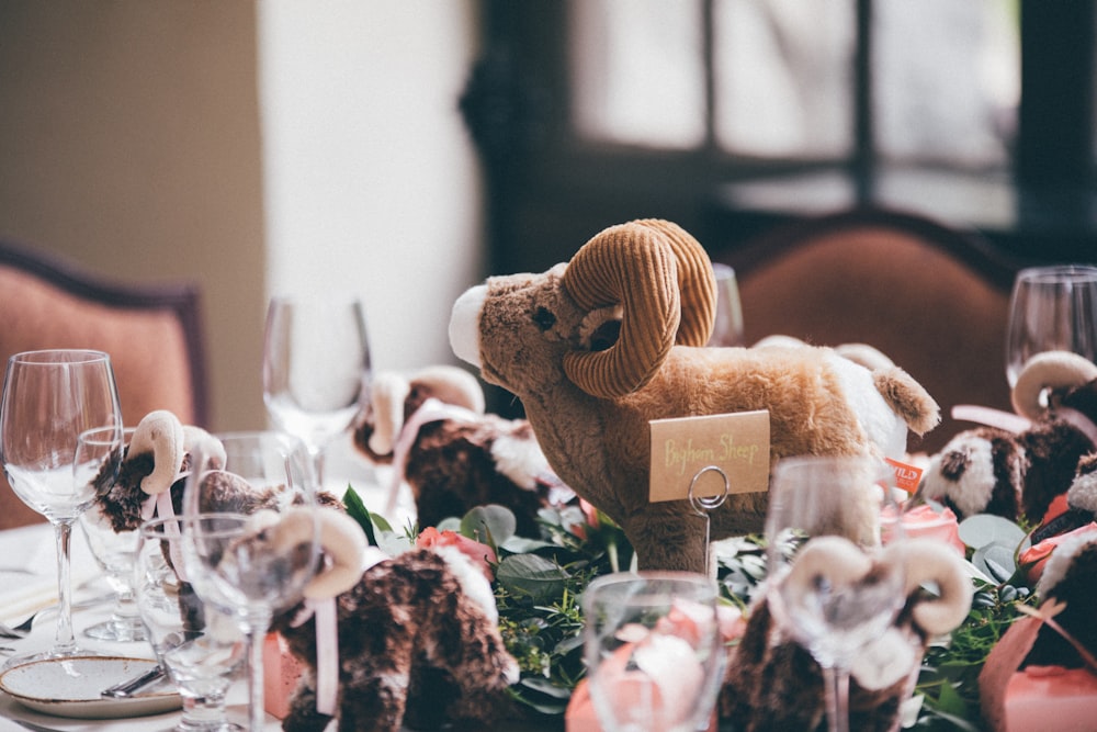 brown ram plush toy beside clear wine glasses