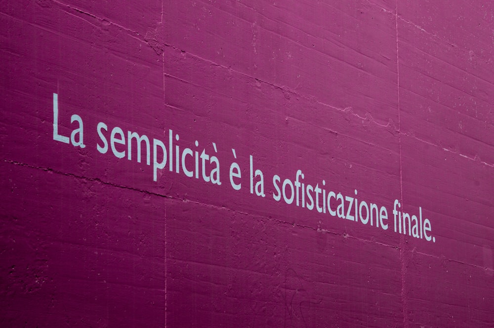 a pink wall with a white writing on it