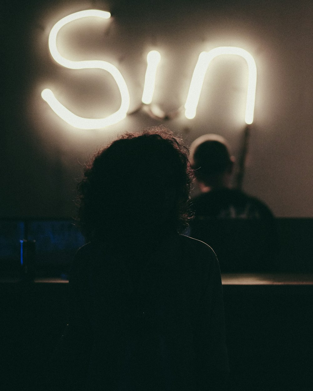 a woman standing in front of a neon sign