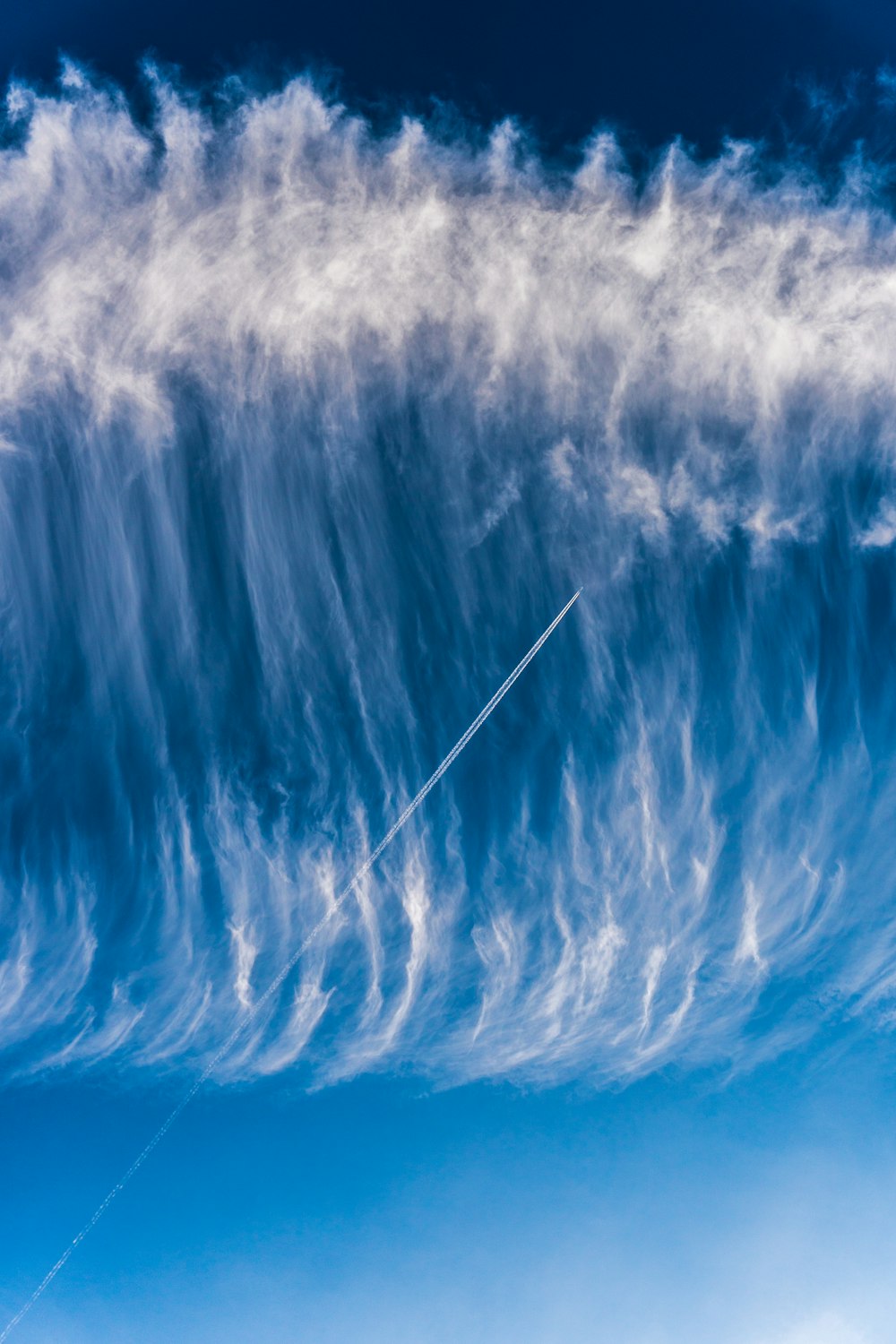 a plane flying through a blue cloudy sky