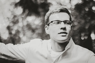 Portrait photo of a male elementary school teacher wearing glasses with a soft blue backdrop