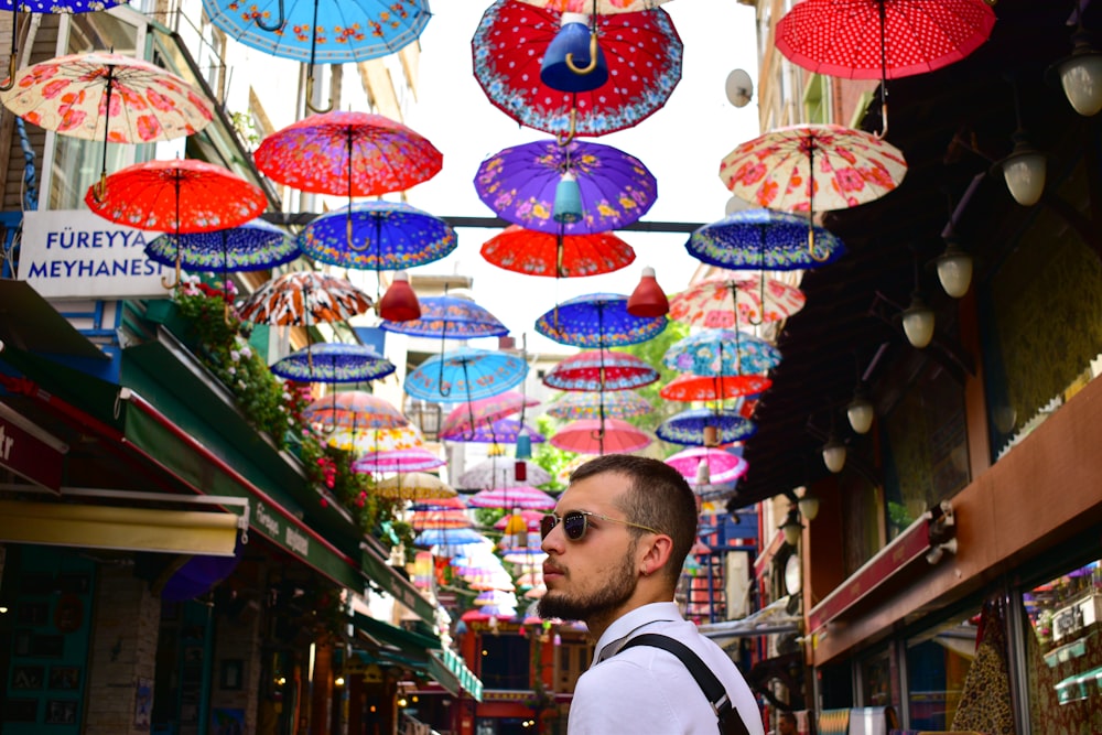 man wearing white dress shirt on street with umbrellas