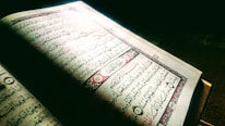 An open book with Islamic calligraphy on a wooden table.