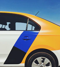 Close-up of a car door wrapped with a colorful, eye-catching advertisement in a busy city street.