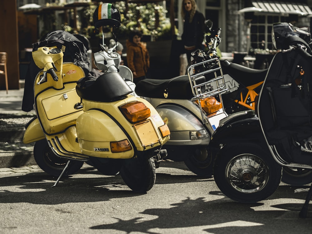 a yellow scooter parked next to a black scooter