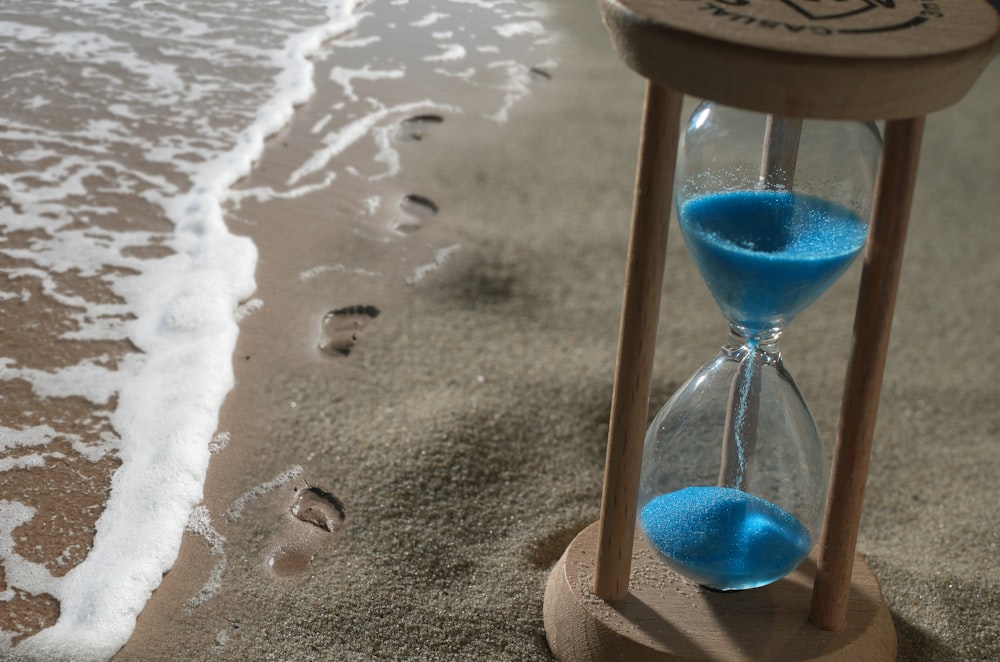 brown hourglass with blue sand on shore