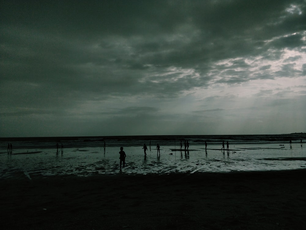um grupo de pessoas em pé no topo de uma praia sob um céu nublado