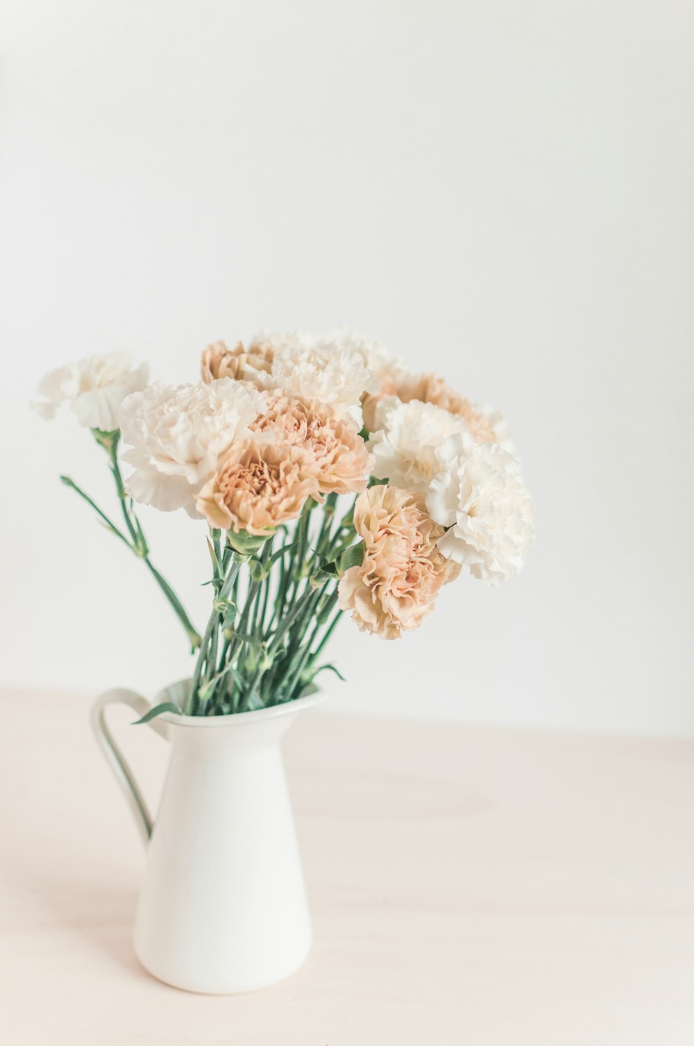 white and beige flowers in a white pitcher