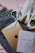 A pair of white sneakers with brown accents, a travel book with a geometric world map design, an Apple iPad, and a pair of blue jeans are laid out on a pink fabric background.