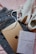 A pair of white sneakers with brown accents, a travel book with a geometric world map design, an Apple iPad, and a pair of blue jeans are laid out on a pink fabric background.