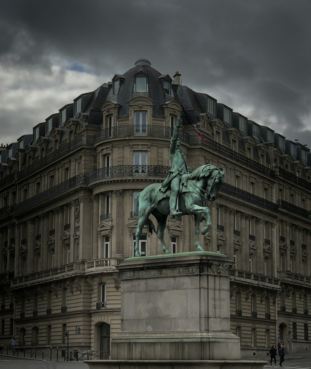 Fotografía de enfoque selectivo de hombre montando estatua de caballo cerca del edificio