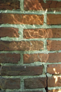 An abstract photo of light and shadow patterns on an old brick wall, evoking a sense of time passing.