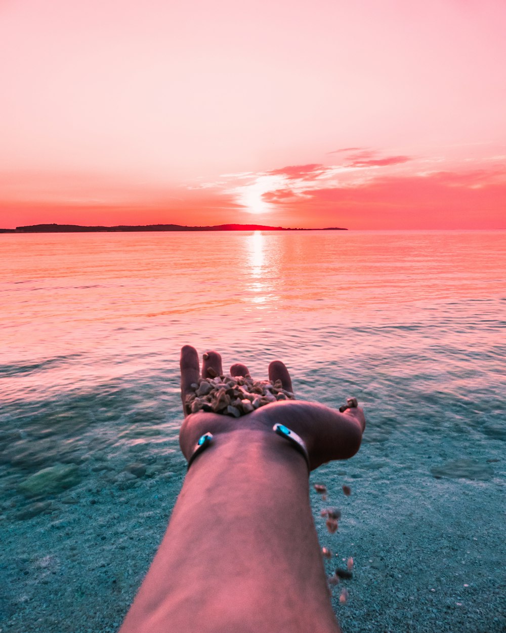 a person with their feet in the sand near the water