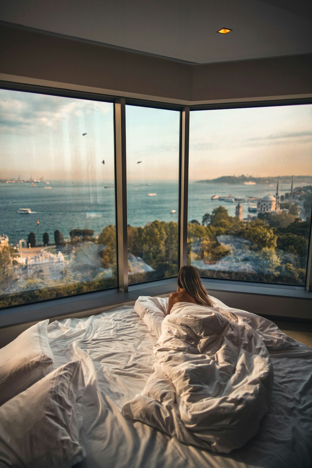 woman lying on bed facing on body of water