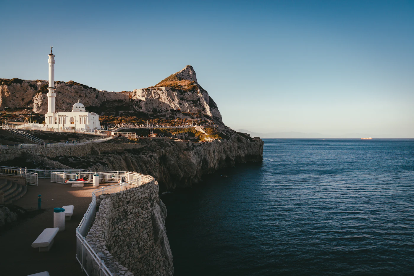 A rocky hillside rising beside a sandy beach and the sea
