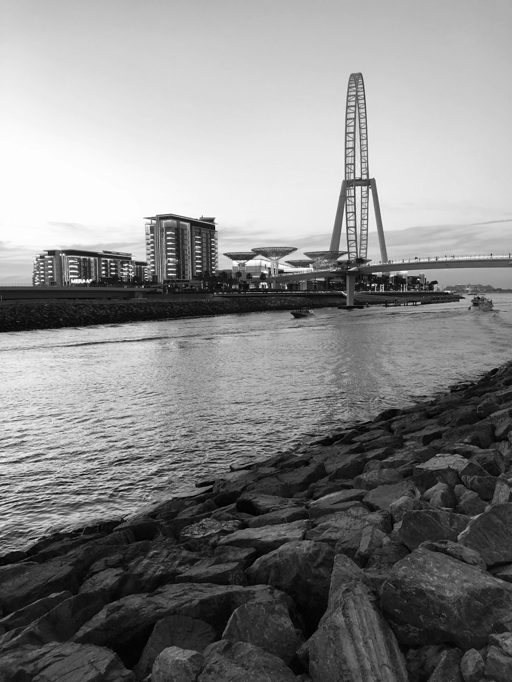 grayscale photo of body of water over bridge facing buildings