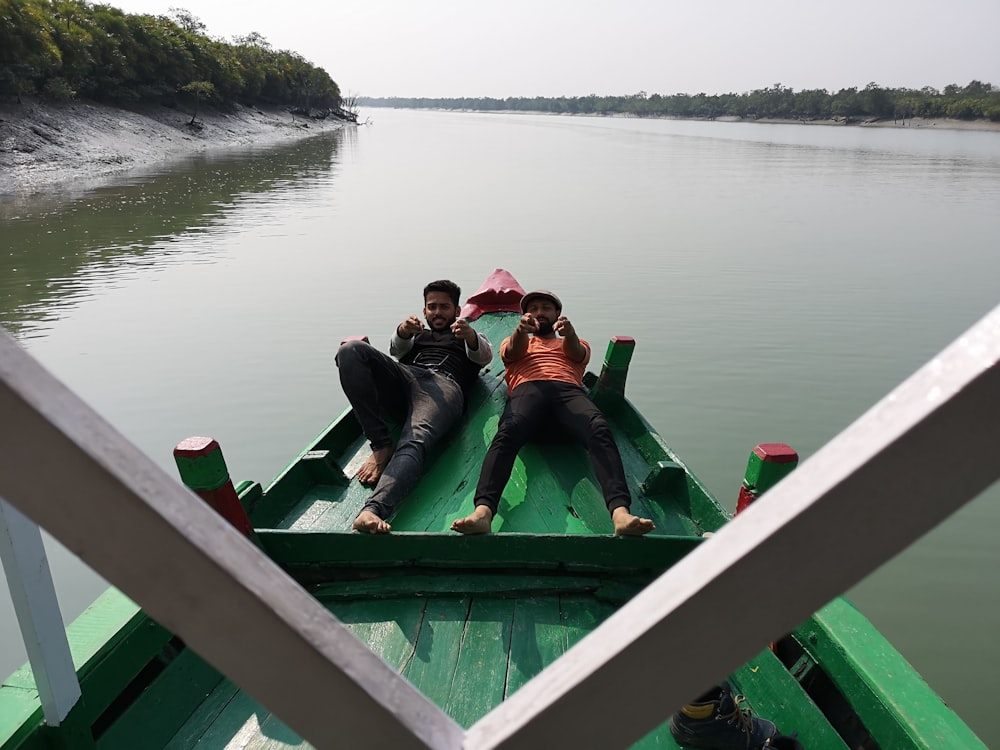 two men lying on green boat photo