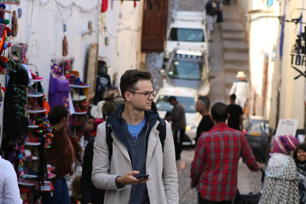 man wearing gray and black jacket holding smartphone