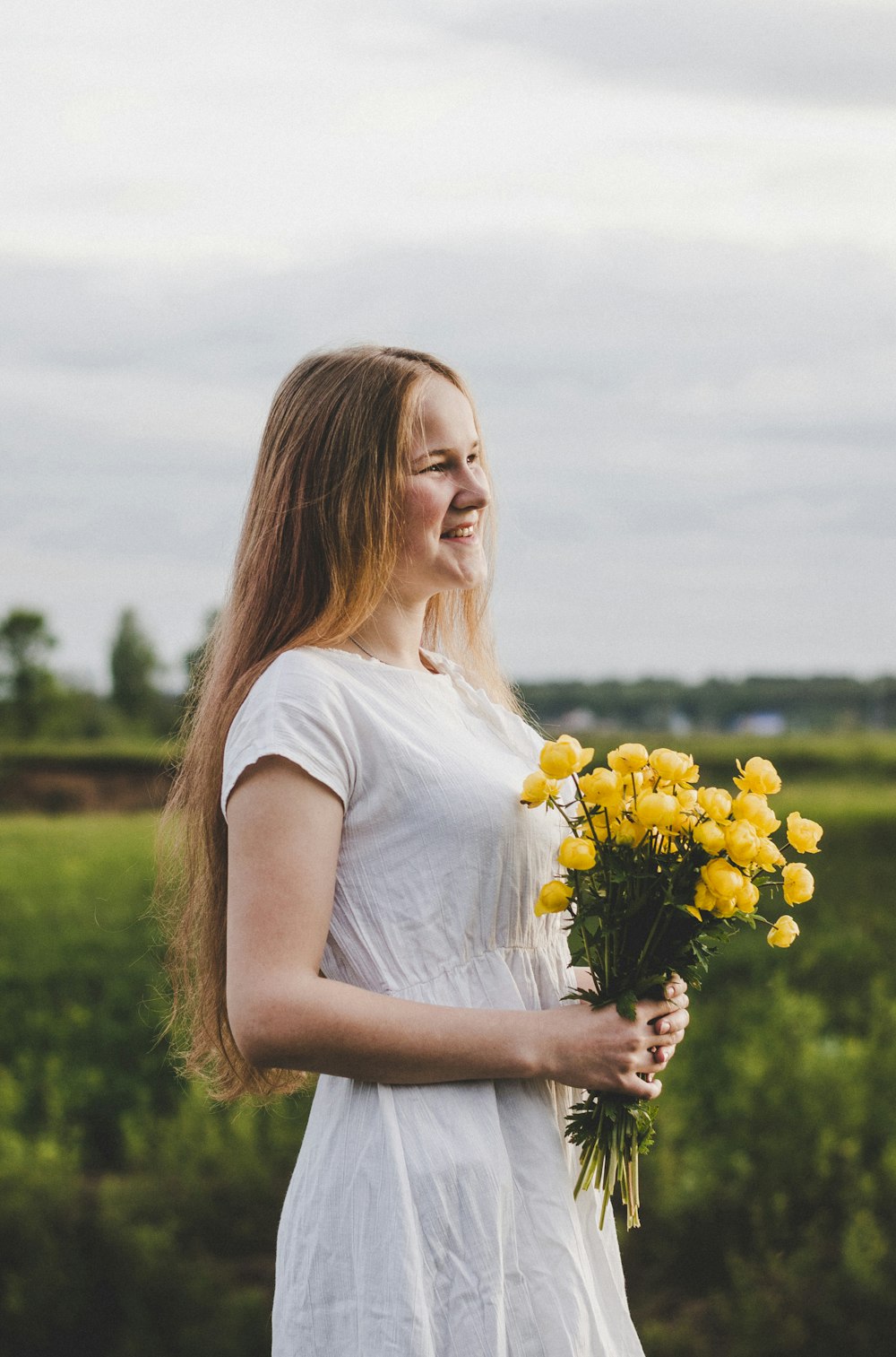 Frau hält einen Strauß gelber Blumen auf dem Feld