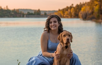woman smiling holding short-coat brown dog