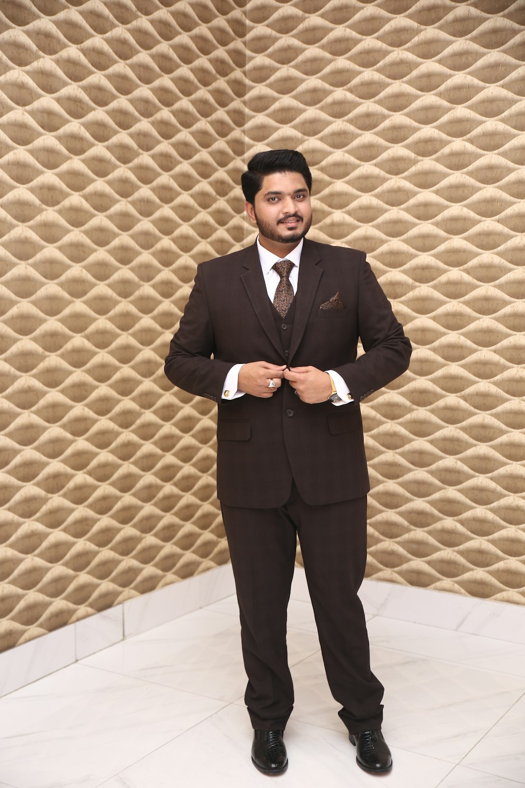 man wearing black suit standing on corner of brown wall