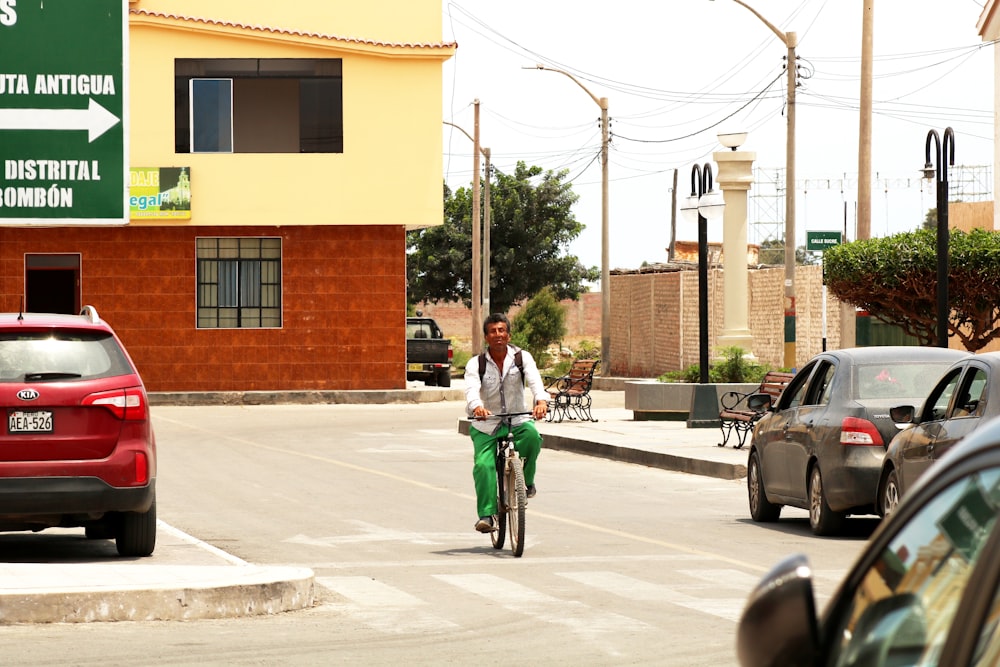 man riding bike near few cars